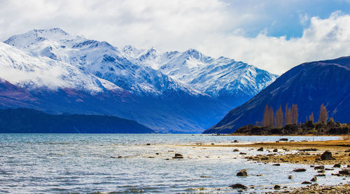 Scenic view of sea and snowcapped mountains against sky