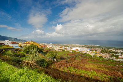 Aerial view of townscape by sea against sky