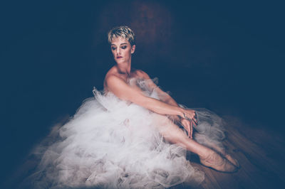 Portrait of young woman against black background