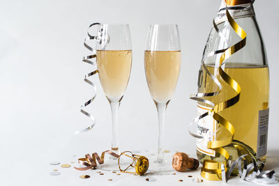 Two champagne glasses and bottle and against white background.