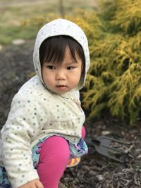 Cute girl in hoodie crouching outdoors