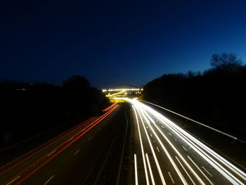 Light trails on road against sky at night