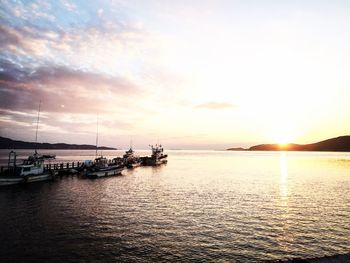 Boats in sea at sunset