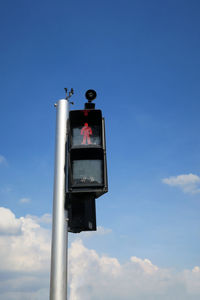 Low angle view of bird perching on pole against sky