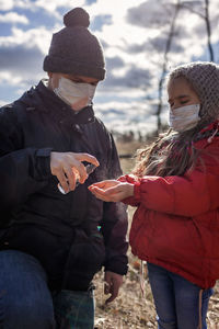 Father and daughter wearing respirator masks staying together on the empty bank of sea