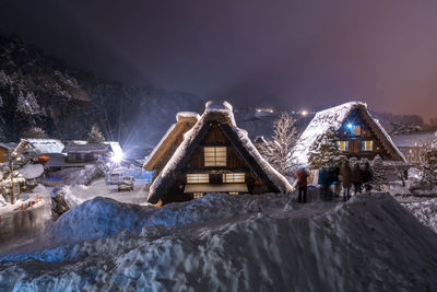 Illuminated buildings against sky at night during winter