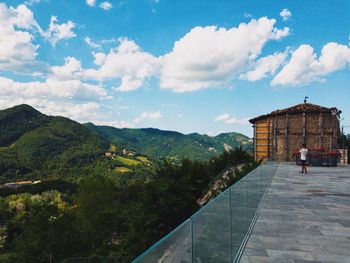 People on building by mountain against sky