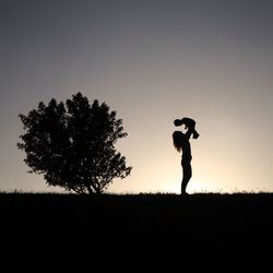 Silhouette of woman standing on field at sunset