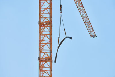 Low angle view of crane against clear blue sky