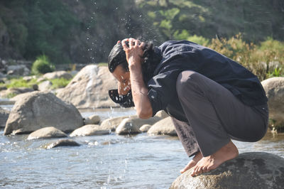 Rear view of man on rock at sea