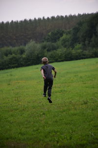 Rear view of boy running on field