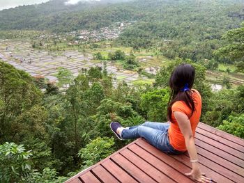 Side view of woman sitting on roof