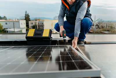 Low section of engineer inspecting solar panel