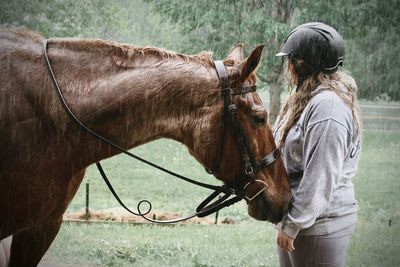 Girl standing in the rain with her horse