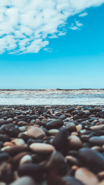 Surface level of stones on beach against blue sky