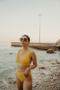 Portrait of young woman - model wearing sunglasses while standing at the beach