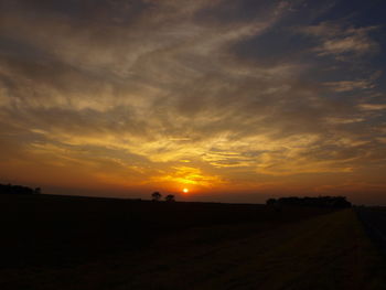Scenic view of silhouette field against orange sky