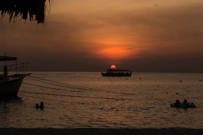 Boat sailing on sea against sky during sunset