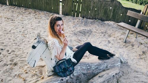 Portrait of young woman smiling and eating ice cream on beach