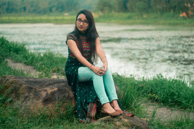 Portrait of young woman sitting on rock