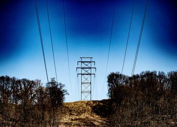 Low angle view of electricity pylon on field