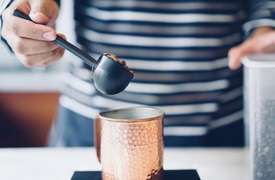 Close-up of hand holding tea cup on table