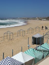 Deck chairs on beach against clear sky