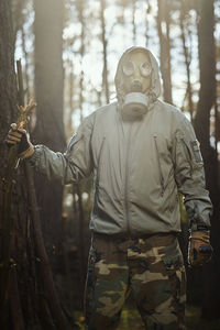 Midsection of man standing by tree in forest