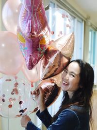 Portrait of smiling woman holding balloons