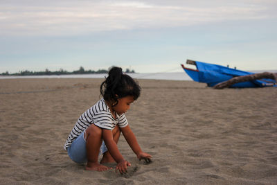 Boy on shore at beach against sky