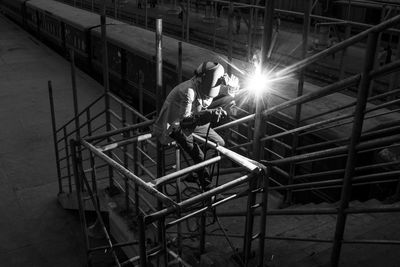 High angle view of welder welding railing at railroad station platform