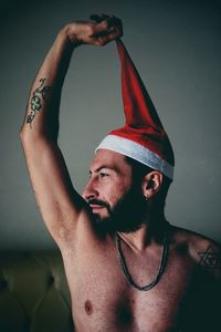 Shirtless man wearing santa hat at home