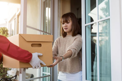 Young woman standing against window