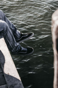 Low section of man sitting by lake