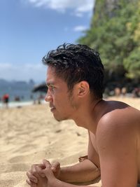 Side view of young woman sitting at beach