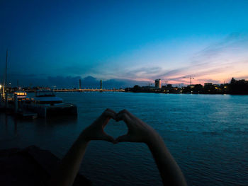 Woman hand by sea against sky in city