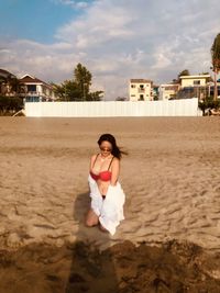 Side view of woman sitting at beach