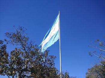 Low angle view of flags against clear blue sky