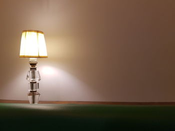 Close-up of illuminated lamp against wall at home