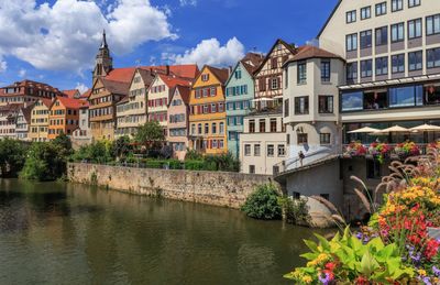 Buildings by river in town against sky