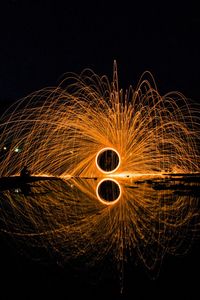 Reflection of burning wire wool on lake at night