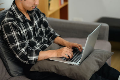 Midsection of woman using laptop at home