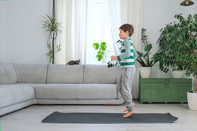 Side view of boy running on mat at home