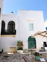 Potted plants on table by building against sky