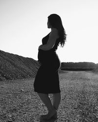 Side view of pregnant woman standing against clear sky