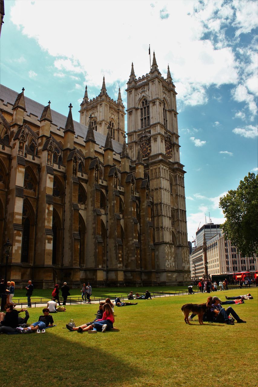 architecture, grass, building exterior, built structure, large group of people, travel destinations, tourism, lawn, travel, tourist, famous place, sky, person, sculpture, city, mode of transport, city life, land vehicle, in front of, facade, tower, day, history, leaning tower of pisa, outdoors, plant, arcade, vacations, international landmark, cloud - sky