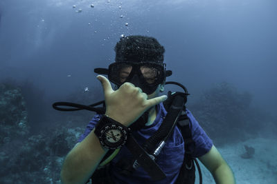 Young boy doing hand signal, doing scuba diving with a compass in the hand