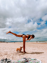 Rear view of woman jumping at beach against sky