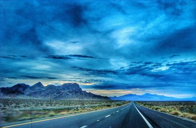 Country road against cloudy sky