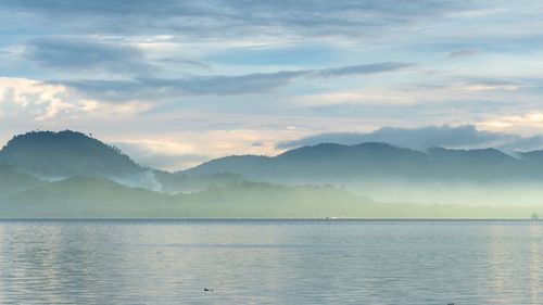 Scenic view of sea and mountains against sky